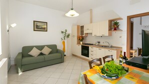 A modern kitchen with a dining area, a sofa, and a radiator. - Apartment 'Agriturismo Case Nuove - Girasole' with Shared Pool, Wi-Fi and Air Conditioning (Castellina Marittima)