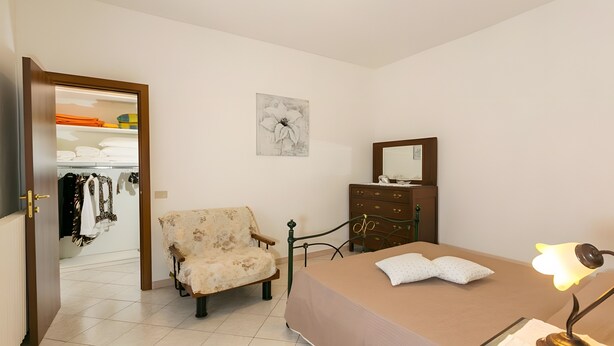 A bedroom with a bed, a chair, a dresser, and a wardrobe. - Apartment 'Agriturismo Case Nuove - Girasole' with Shared Pool, Wi-Fi and Air Conditioning (Castellina Marittima)