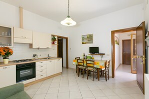 Eine kompakte Küche mit Essbereich, einem Fernseher und einer Tür zu einem weiteren Zimmer.