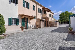 Ein Gebäude mit einem Kieshof, einer Holzw pergola und einem überdachten Sitzbereich.