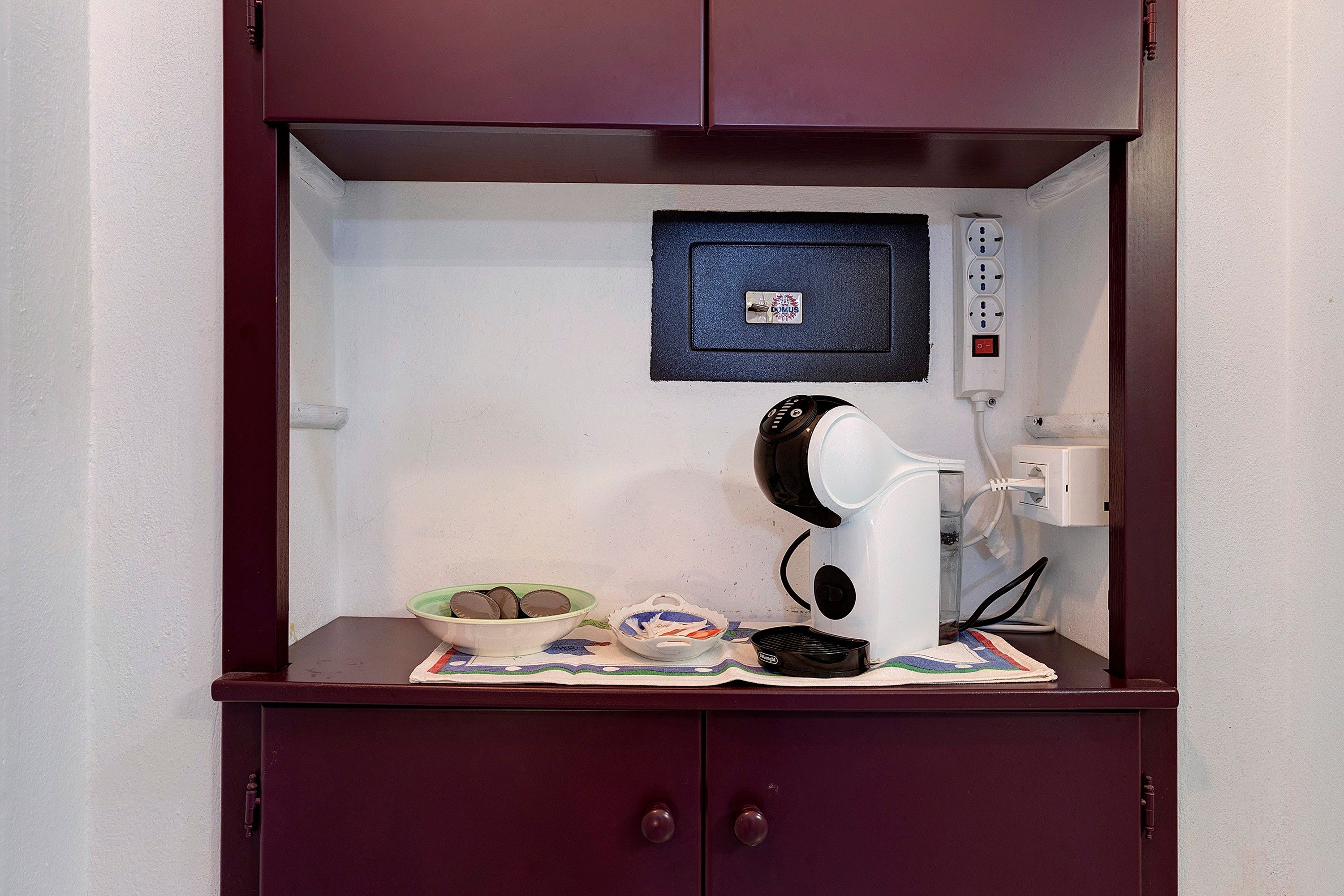 A kitchenette with a coffee maker, a bowl of cookies, and a power strip.
