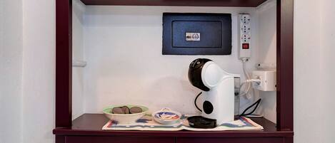 A kitchenette with a coffee maker, a bowl of cookies, and a power strip.