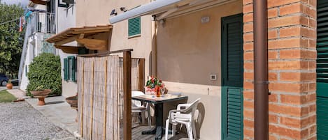 Un edificio con terraza, una mesa con sillas y una planta en maceta.