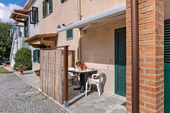 A building with a terrace, a table with chairs, and a potted plant.