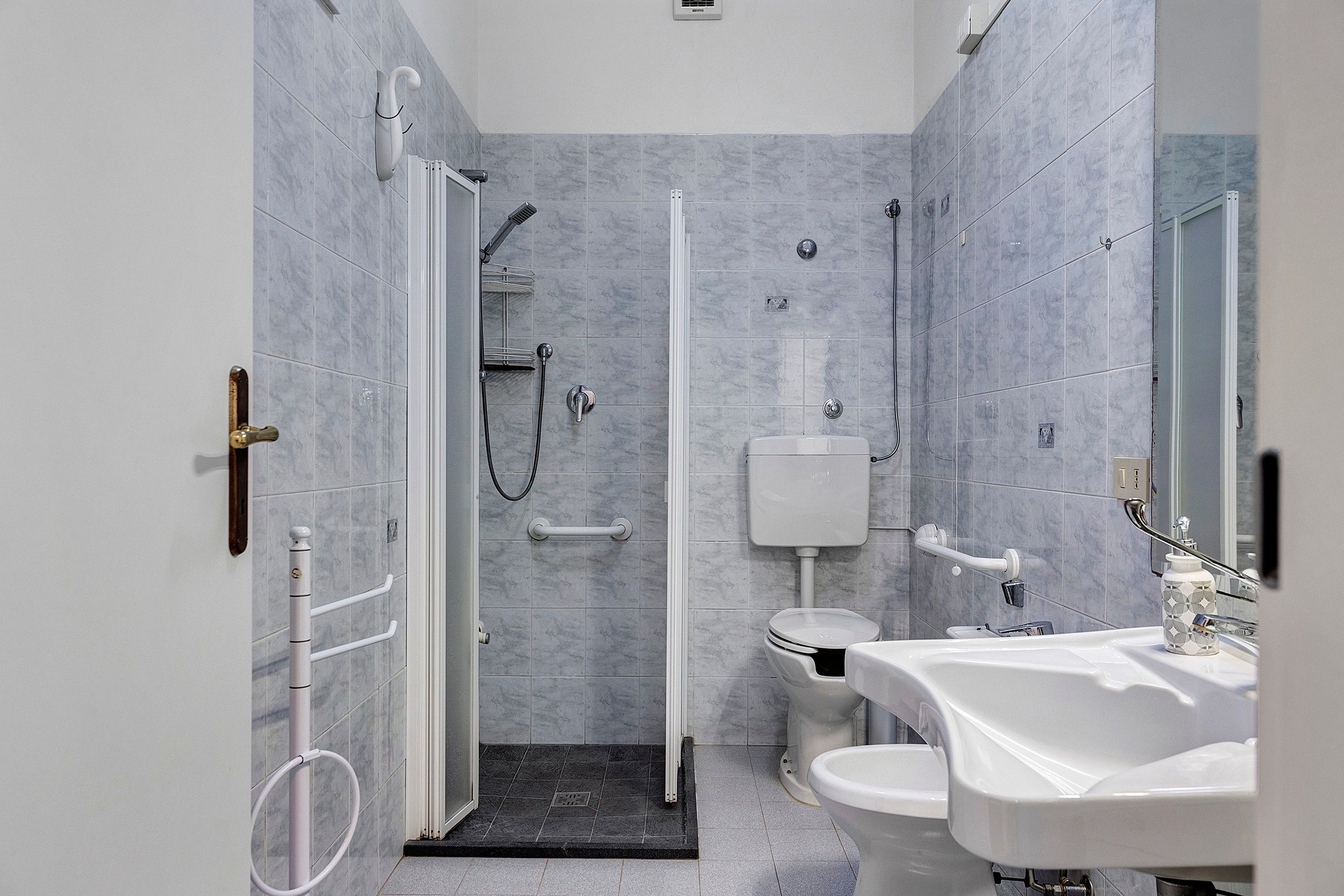 Ein modernes Badezimmer mit barrierefreier Dusche, Toilette und Waschbecken.