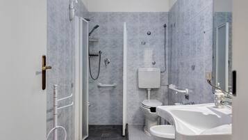Ein modernes Badezimmer mit barrierefreier Dusche, Toilette und Waschbecken.