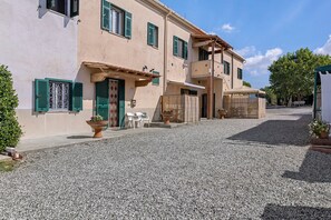 Un bâtiment doté d’une cour en gravier, d’une pergola en bois et d’un espace de détente extérieur.
