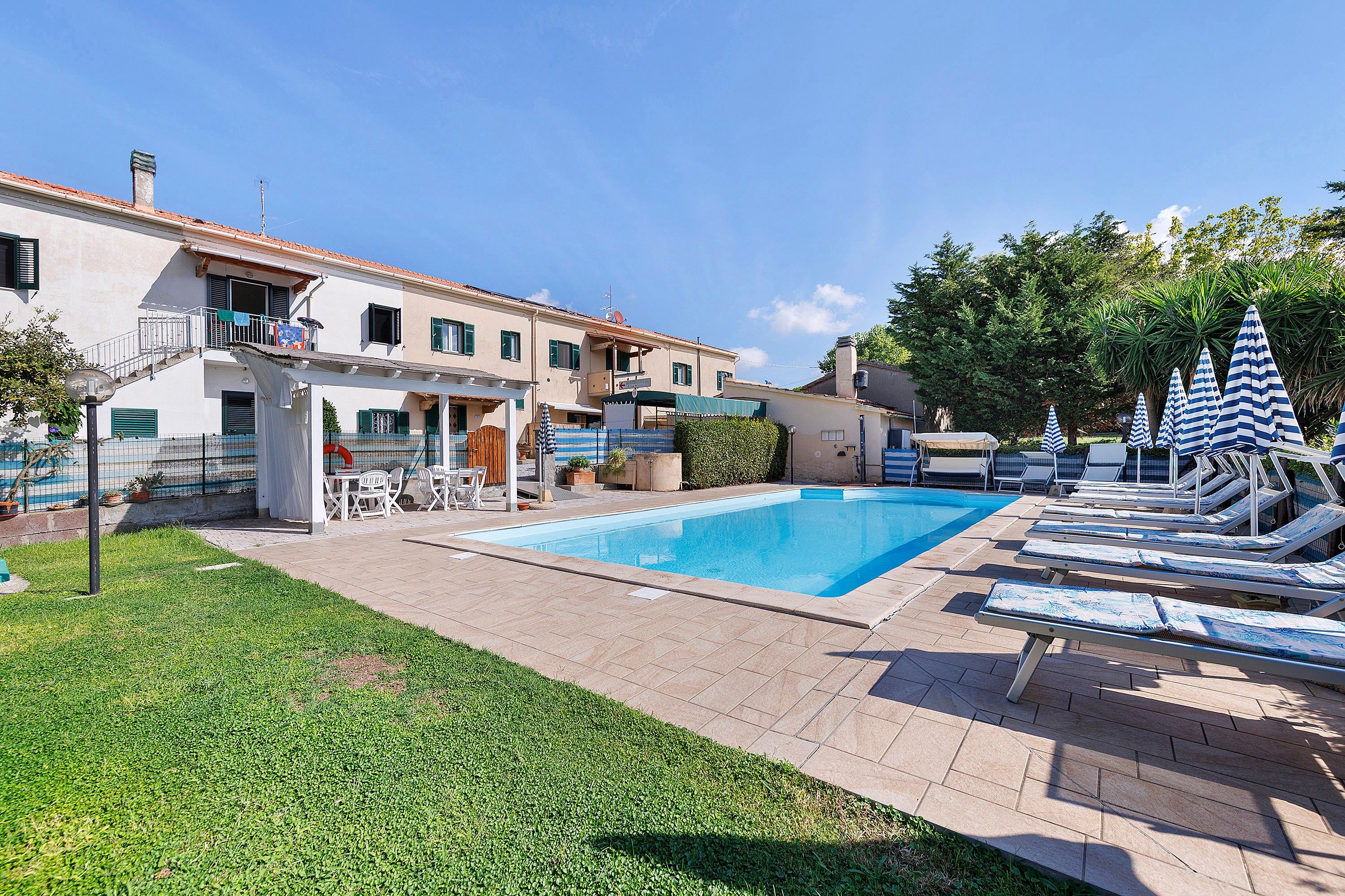 Una piscina con lettini e una zona relax coperta.