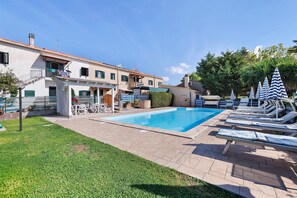 A swimming pool with lounge chairs and a covered seating area.