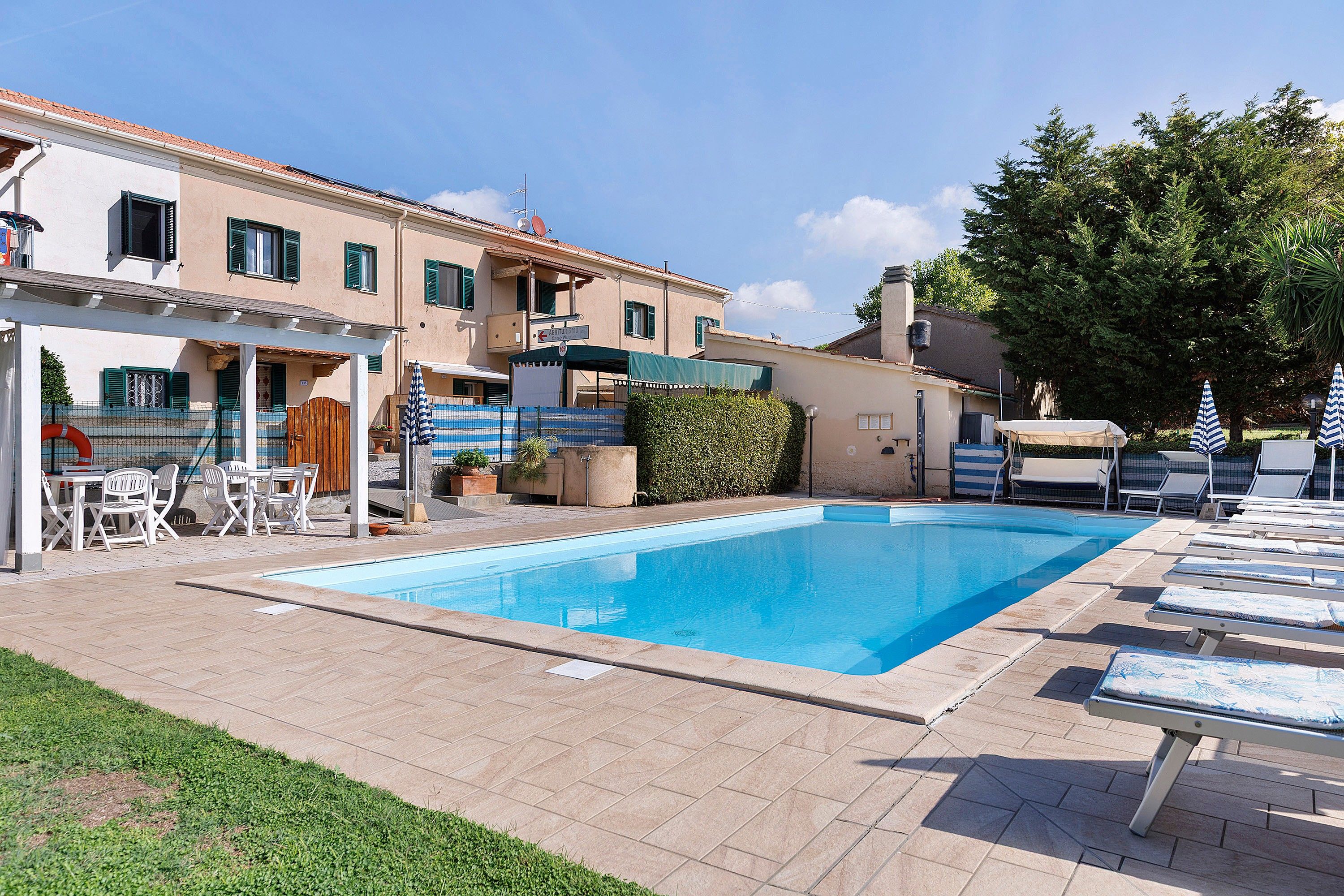 A swimming pool with lounge chairs and a covered seating area.