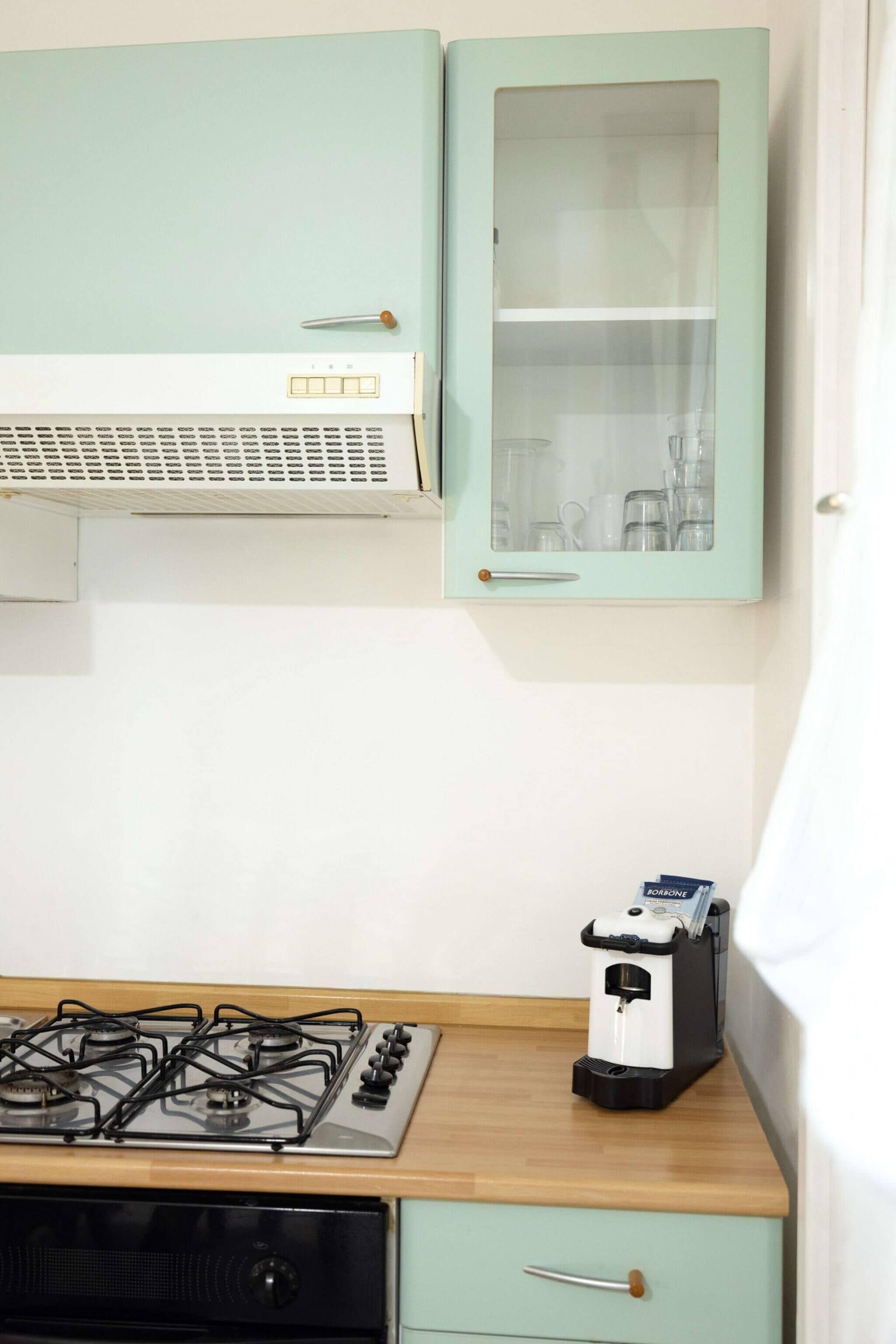 A kitchen with a gas stove, a microwave, and a cabinet with a glass door.