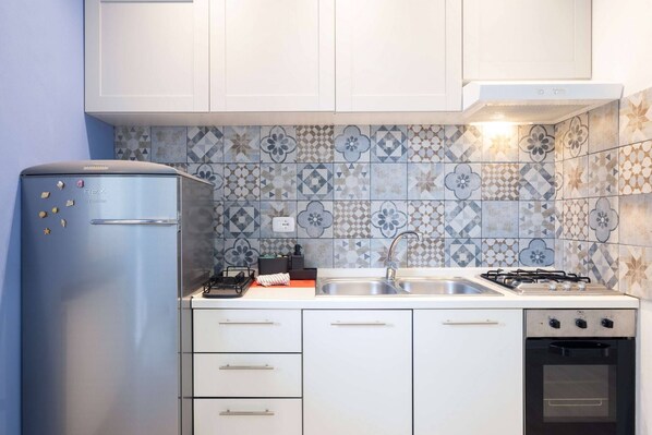 A kitchen with a blue refrigerator, a gas stove, a sink, and a built-in oven. - Charming Modern Loft With Sea View in Riccione Hills (Riccione)