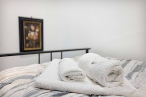 A bed with rolled white towels and a framed picture on the wall. - Charming Modern Loft With Sea View in Riccione Hills (Riccione)
