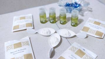 A table with packets of Bonnet de douce, small bottles of green liquid, and white spoons.
