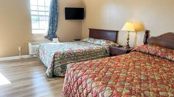 Une chambre d’hôtel avec deux lits, une télévision, une lampe et une fenêtre avec des rideaux.