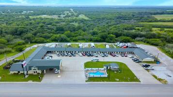 An RV parking lot with a swimming pool, surrounded by a large building with a sign.