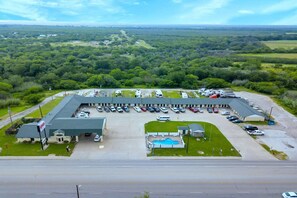 An RV parking lot with a swimming pool, surrounded by a large building with a sign.
