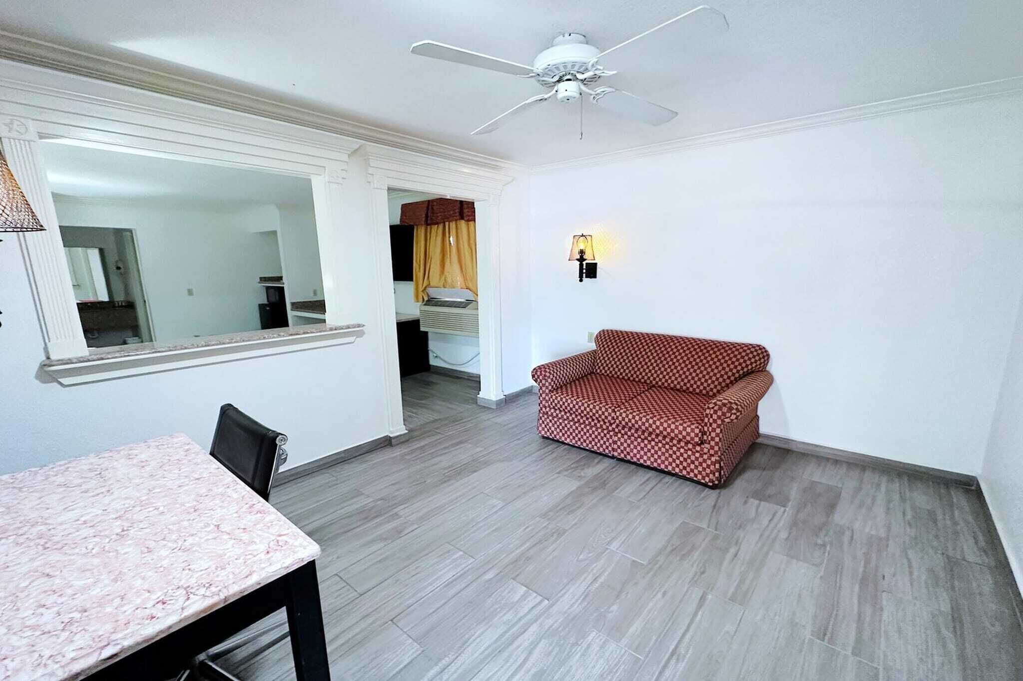 Una habitación con ventilador de techo, sofá, mesa de comedor y espejo.