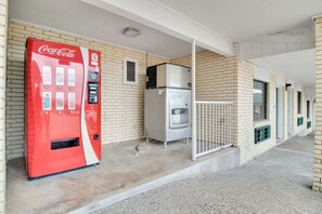 Una máquina expendedora de Coca-Cola, un refrigerador y una entrada cerrada a un edificio de fachada de ladrillo.