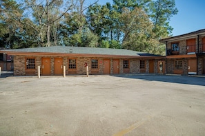 A two-story building with a brick facade, multiple doors, and a parking lot in front. - Deluxe 2 Full Beds | Walterboro (Walterboro SC)
