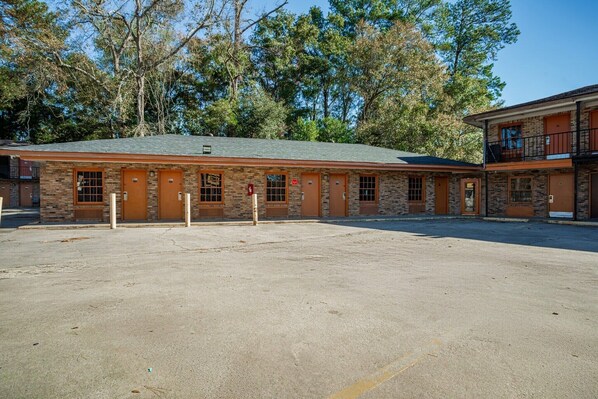 A two-story building with a brick facade, multiple doors, and a parking lot in front.