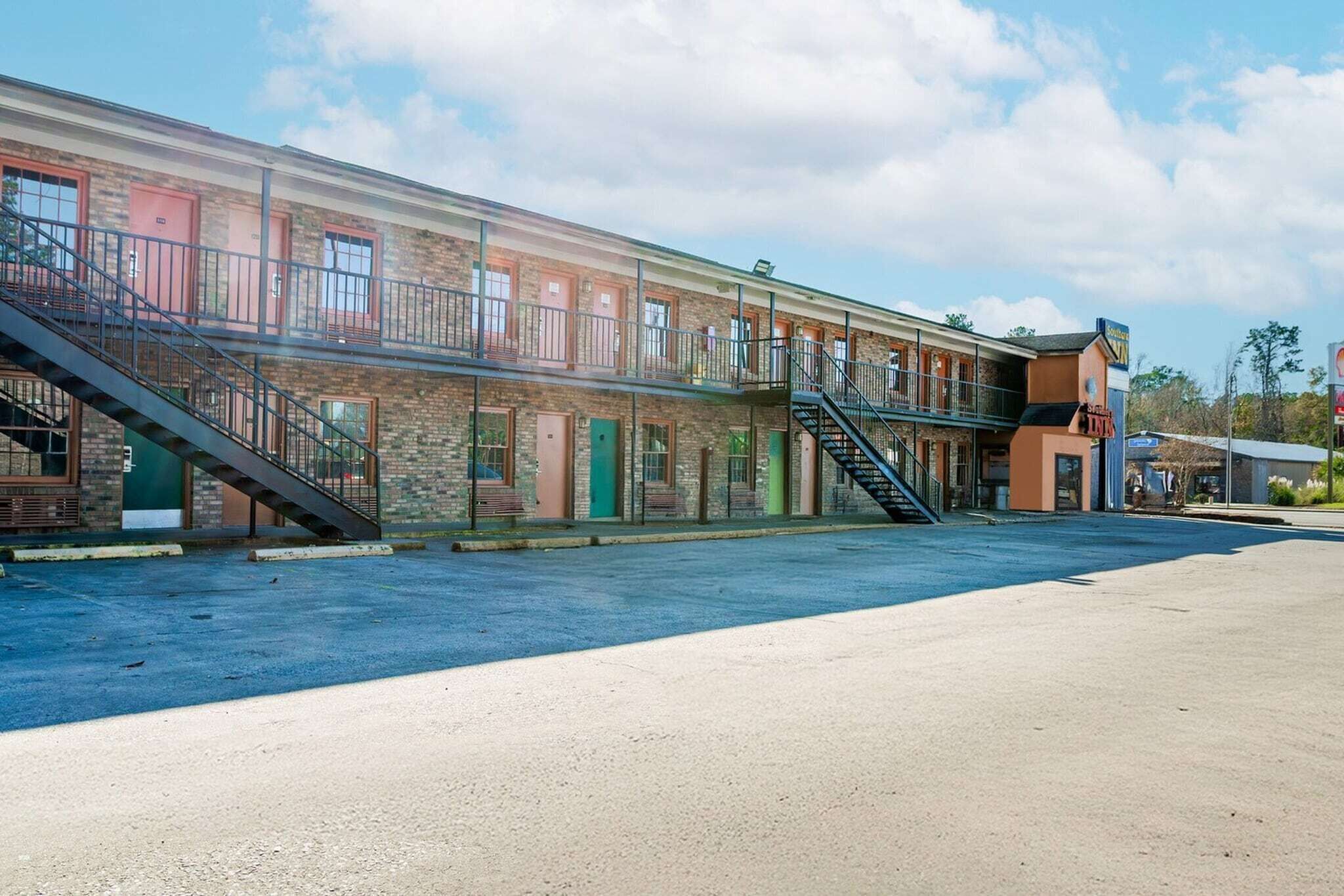 A multi-story building with a brick facade, a covered outdoor area, and a staircase leading to the upper floors.
