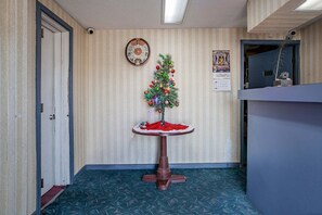 A hallway with a Christmas tree on a pedestal, a clock on the wall, and a calendar. - Deluxe 2 Full Beds | Walterboro (Walterboro SC)