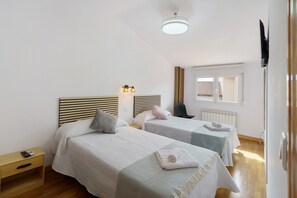 Et hotelværelse med to senge, et natbord, en stol, et vindue med udsigt og en loftlampe.