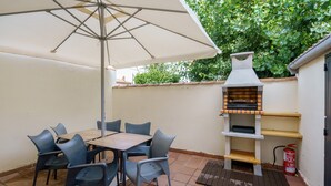 Een terras met een tafel, stoelen, een barbecue en een brandblusser.