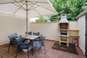 Un patio con mesa y sillas, una parrilla y un extintor.
