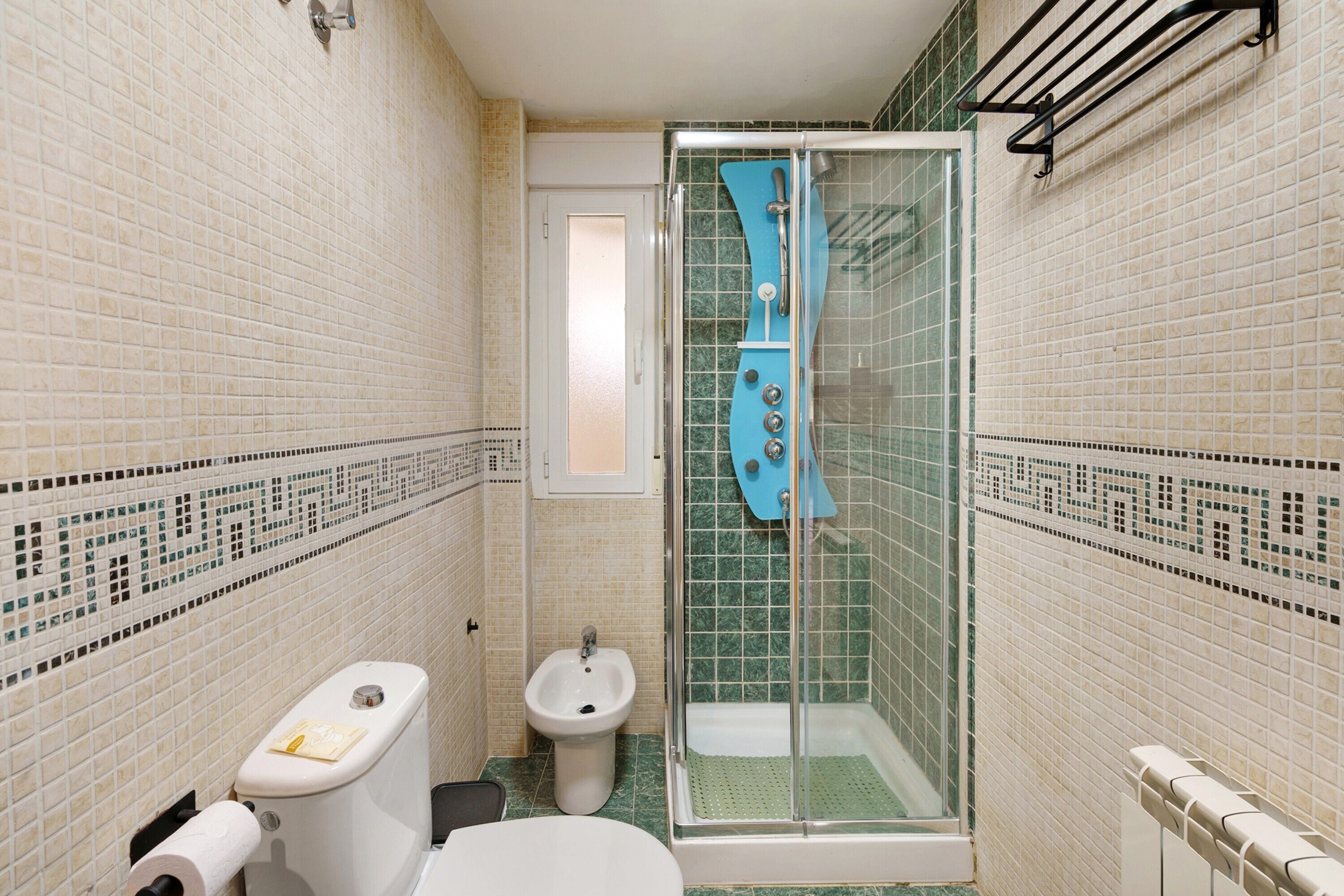 Een kleine badkamer met toilet, bidet en een douchecabine.