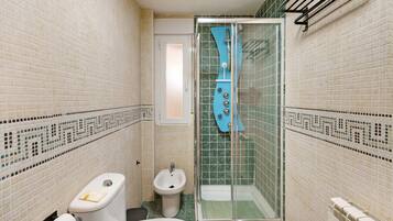 Een kleine badkamer met toilet, bidet en een douchecabine.