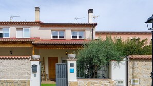 Una casa de dues plantes amb teulada de rajola, façana de pedra i entrada tancada per una reixa.