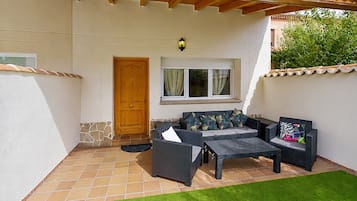 Un porche cubierto con una zona de estar, una puerta y una ventana con cortinas.