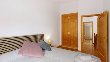 A bedroom with a bed, pillows, a bedside lamp, a wardrobe, and a mirror.