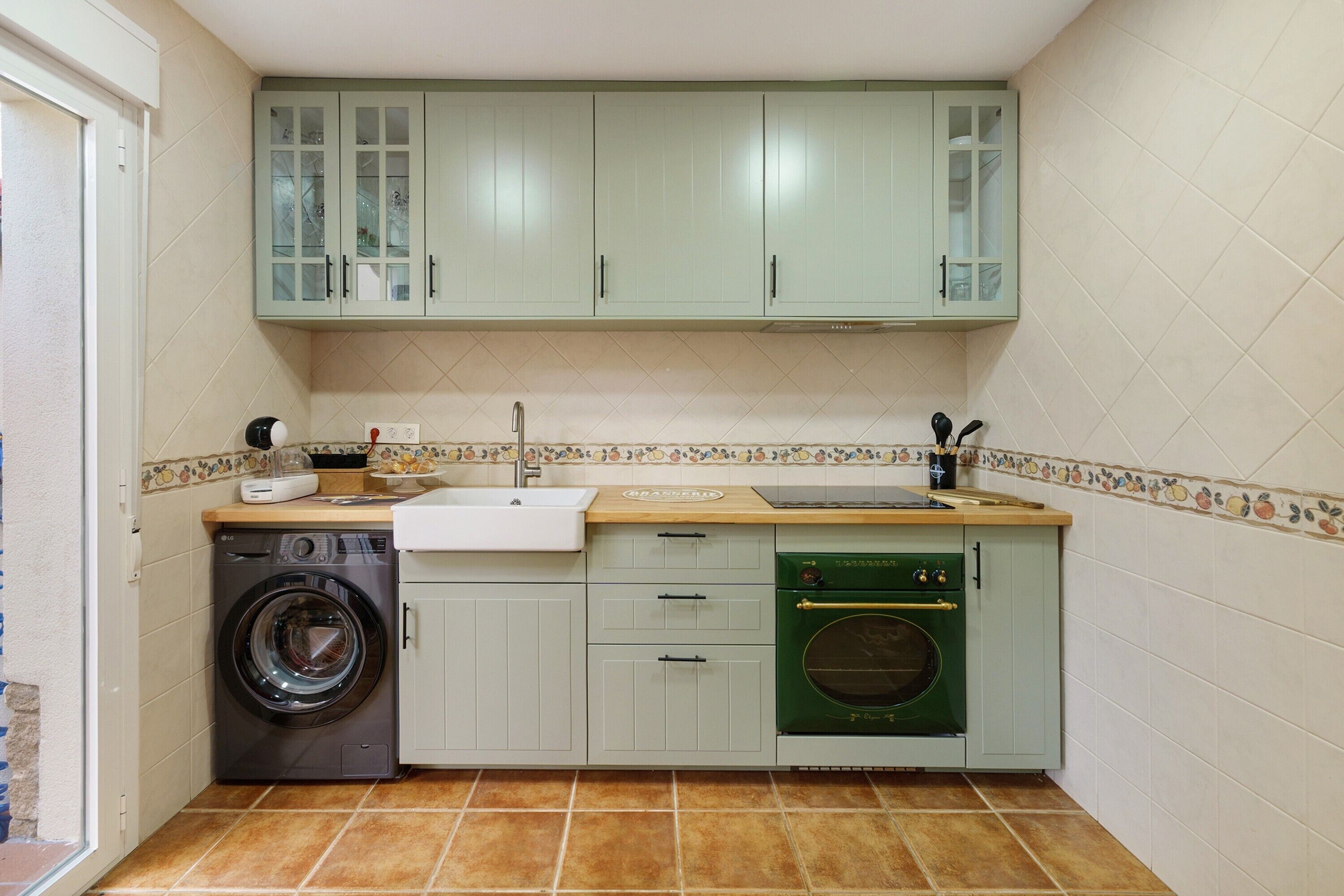 Een compacte keuken met een wasmachine, vaatwasser en een klein oven.