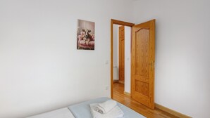 Un dormitori amb llit, una porta i un quadre penjat a la paret.