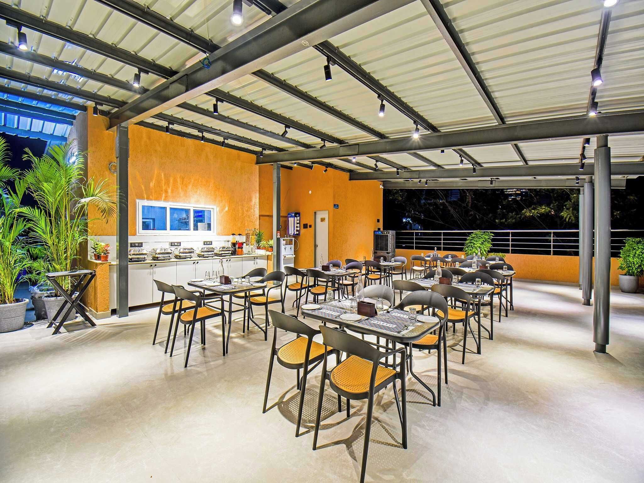 En restaurang med uteservering, ett köksområde och krukväxter.