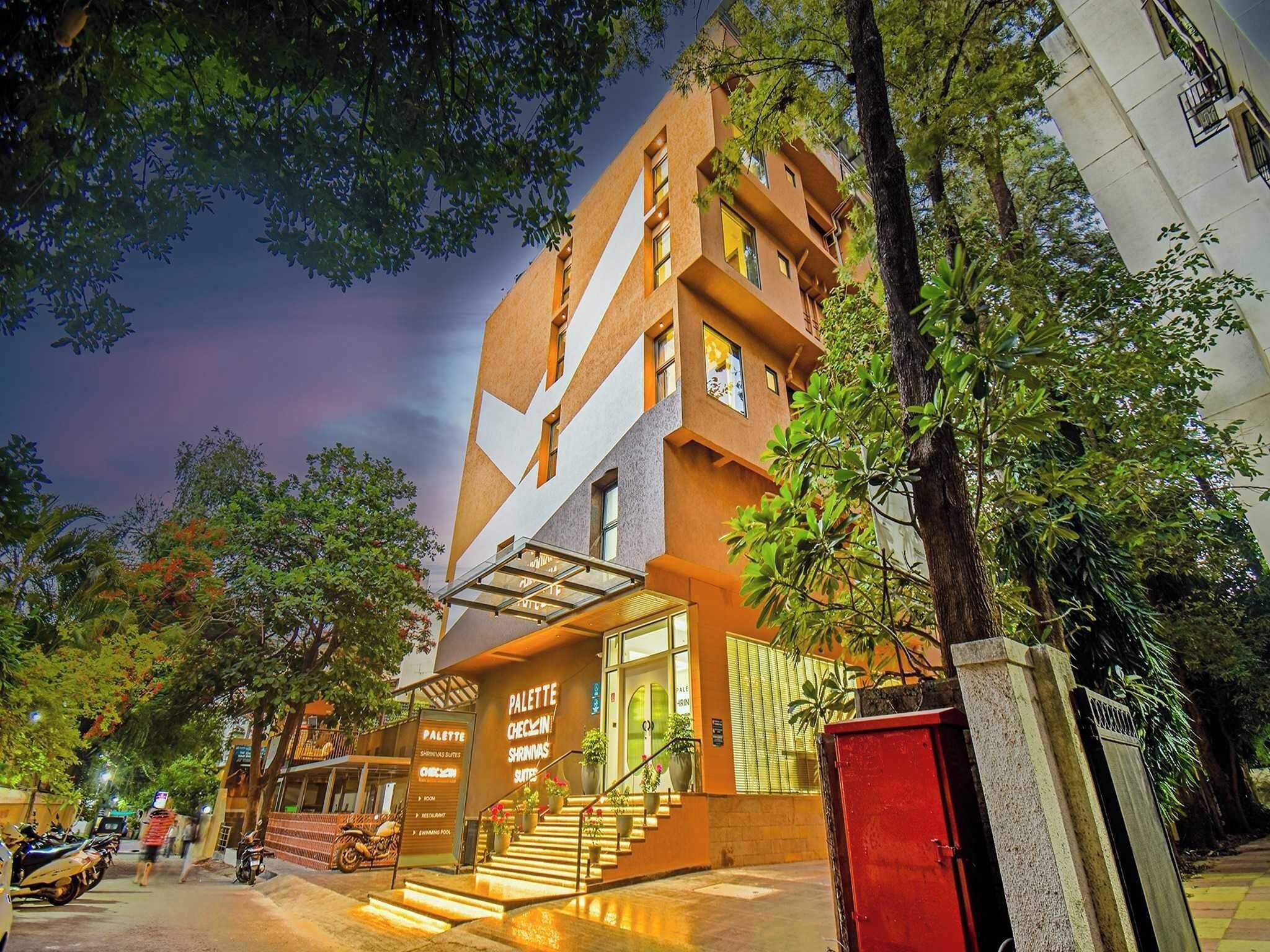 A modern hotel with a unique geometric facade, outdoor seating area, and a staircase leading to the entrance.
