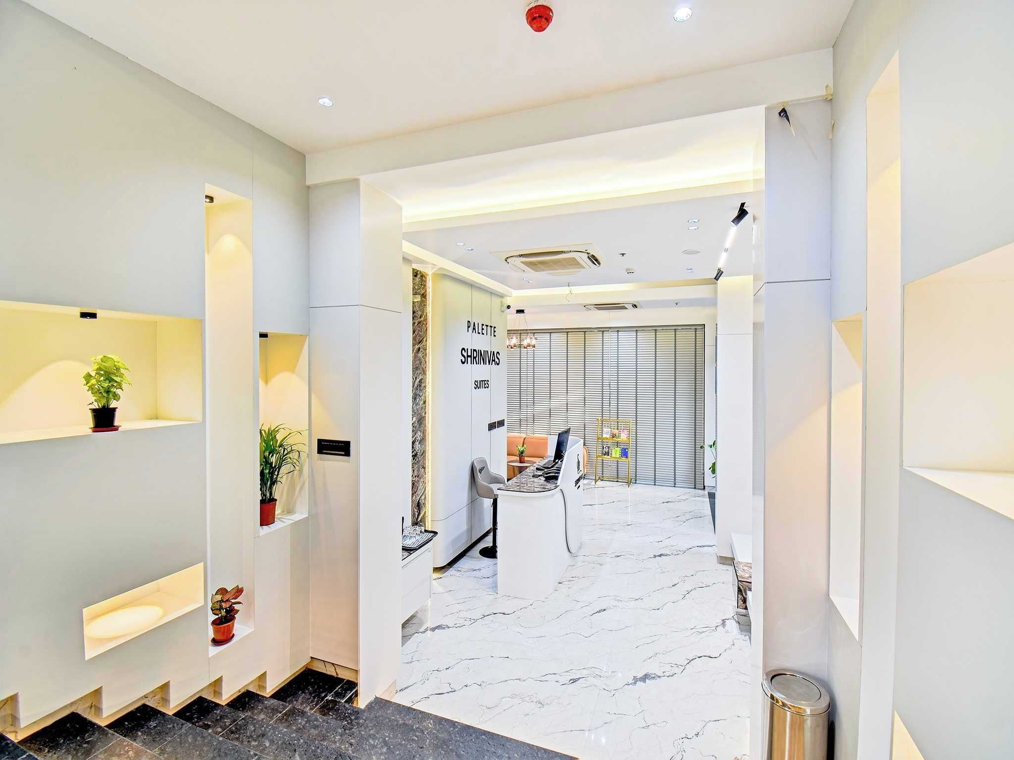 Un moderno vestíbulo de hotel con piso de mármol, una recepción y un área de estar con un sofá y una mesita.