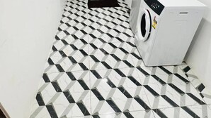 A laundry room with a checkered floor, two doors, and a washing machine.