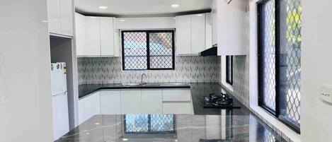 A modern kitchen with white cabinets, a black countertop, and a window with a metal grid.