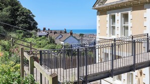 Eine Wohngegend an der Küste mit Blick auf das Meer, einer Holztreppe und einem Gebäude mit einer beige farbenen Fassade.