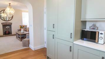 A modern kitchen with light-colored cabinets, a microwave, and a decorative glass item on the countertop.