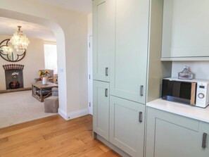 A modern kitchen with light-colored cabinets, a microwave, and a decorative glass item on the countertop. - Sea Vista (Bideford)