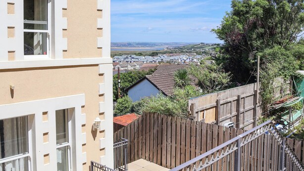Ein Wohngebäude mit Balkon, Holzzaun und Blick auf eine Stadt und Landschaft.