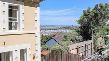 A residential building with a balcony, a wooden fence, and a view of a town and landscape.