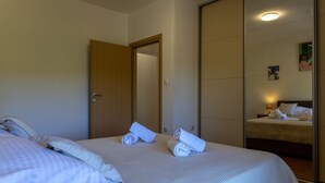 Ein Hotelzimmer mit einem Bett, einer Holztür, einem Spiegel und einer Wand mit einem Gemälde.
