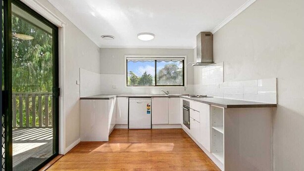 A modern kitchen with white cabinets, a wooden floor, and a window providing natural light. - HAVELI...... (Metung)