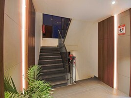 Una escalera con barandilla metálica, un letrero de salida de incendios y una planta en maceta.
